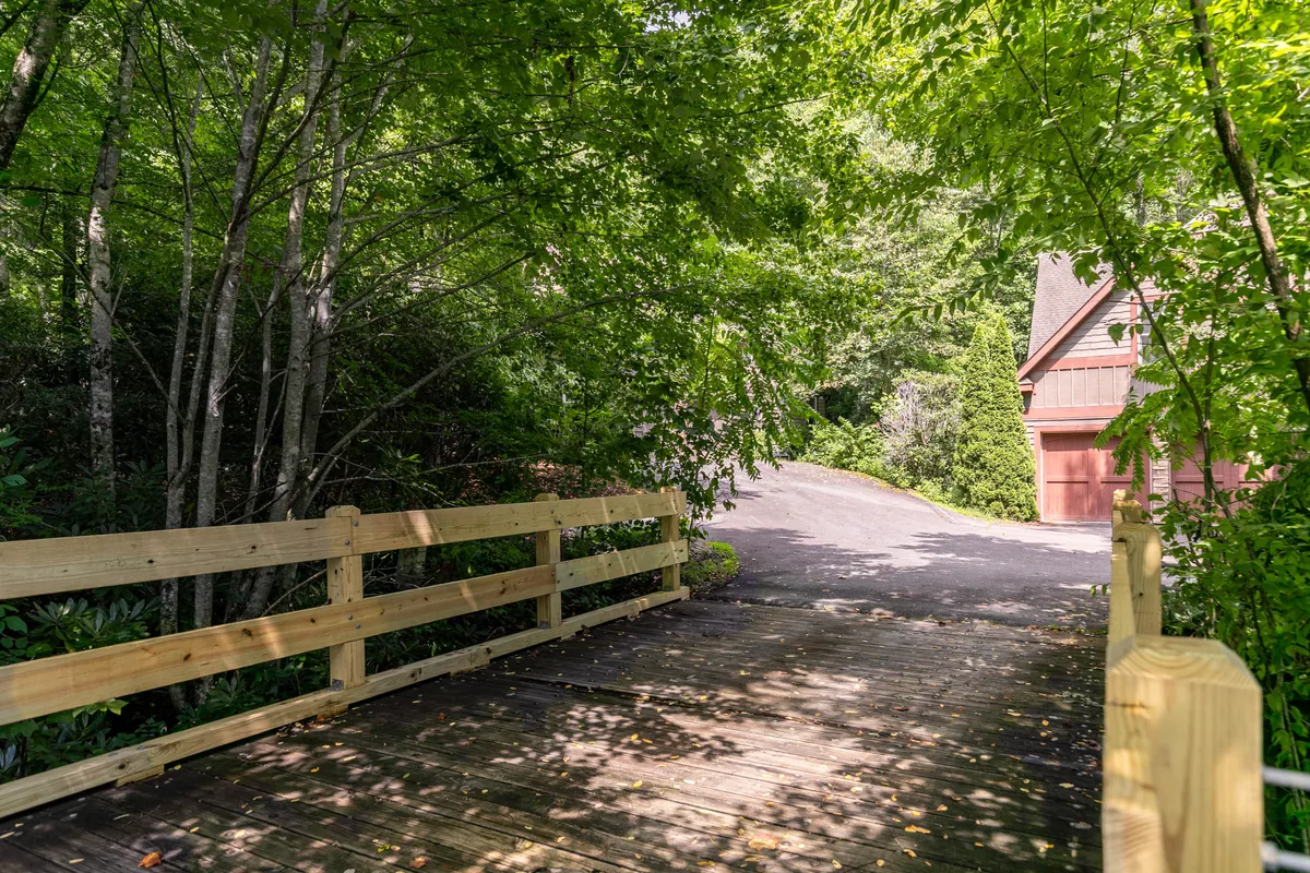 A tranquil wooden bridge surrounded by lush trees, with a gentle creek flowing nearby. The setting evokes peaceful moments of reflection and connection with the natural environment.