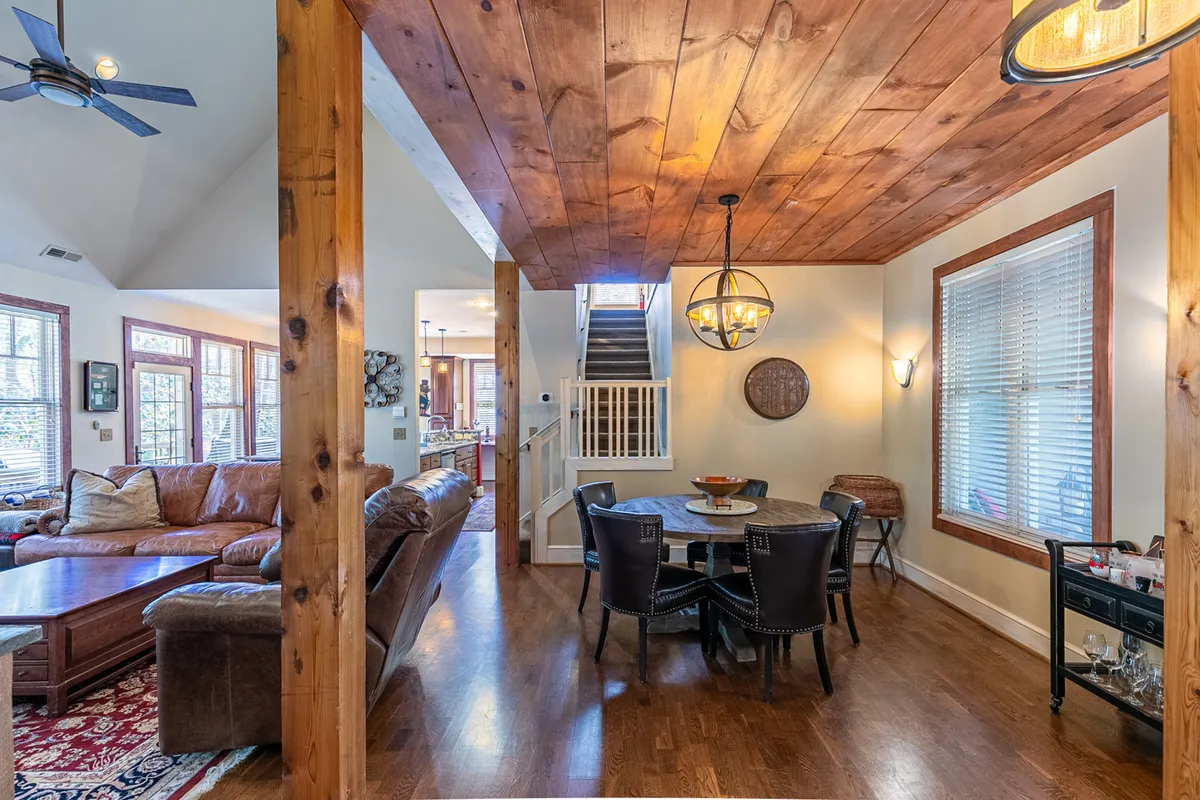 A warm, family-oriented scene displaying a large dining table with seating for many, a comfortable sofa nearby, exposed wooden beams, and a statement light fixture. The ambiance is lively yet cozy, perfect for group gatherings and shared celebrations.